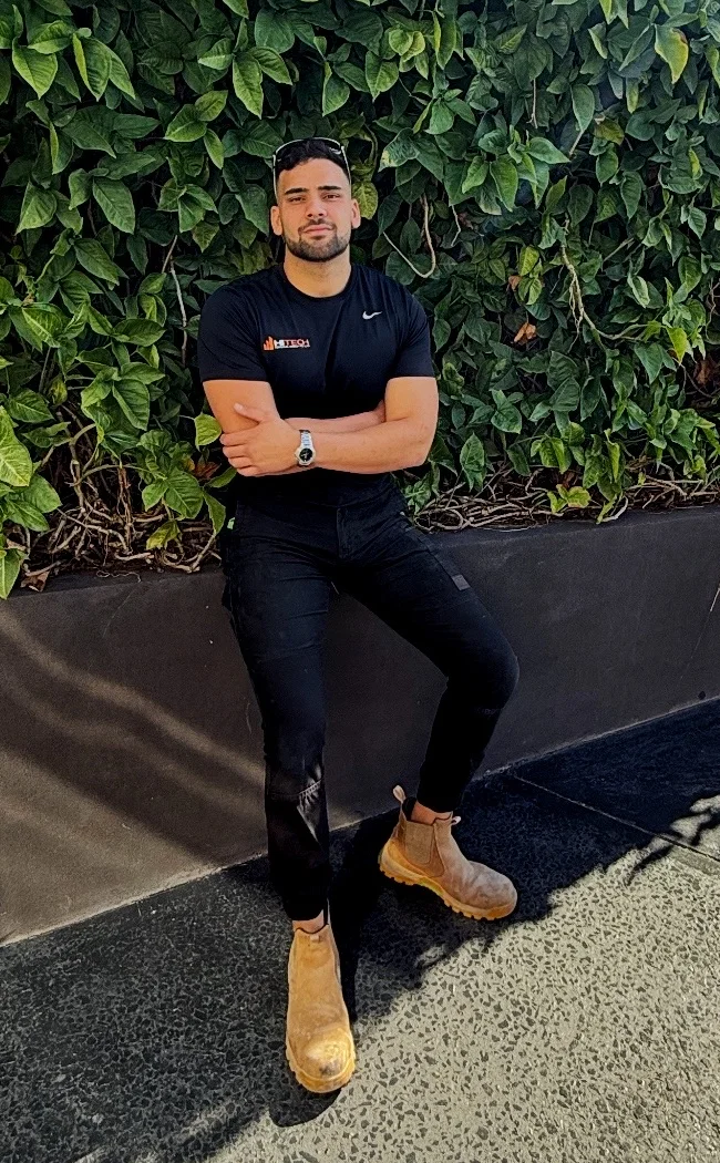 Eren Karaerik, founding manager of HiTech Remedial Group, in front of a leafy wall